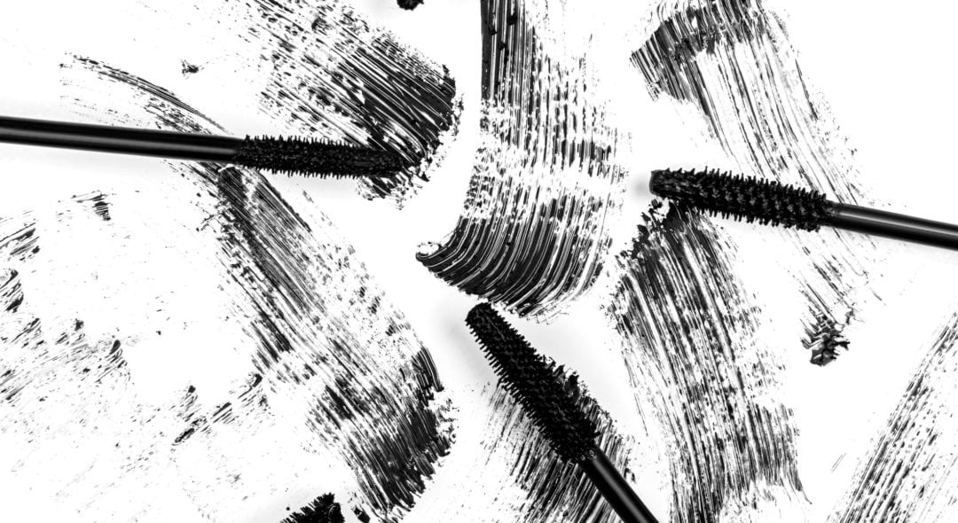 Black smear mascara and brushes on white background. Isolated. Makeup. Cosmetic products for eyelashes. Closeup. Beautiful pattern.