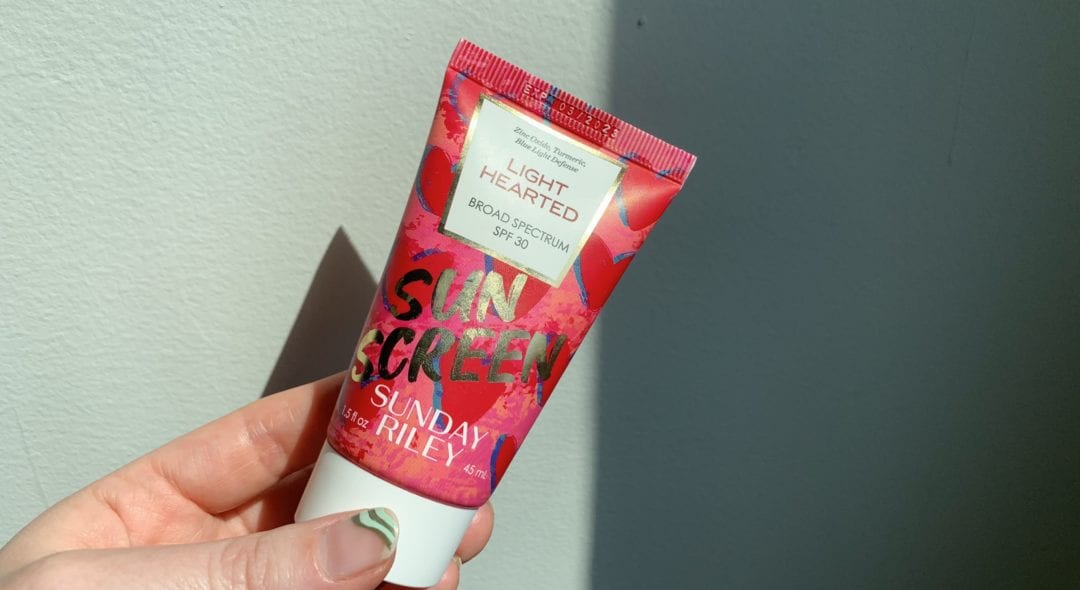 hand holding Light Hearted SPF sunscreen Sunday Riley