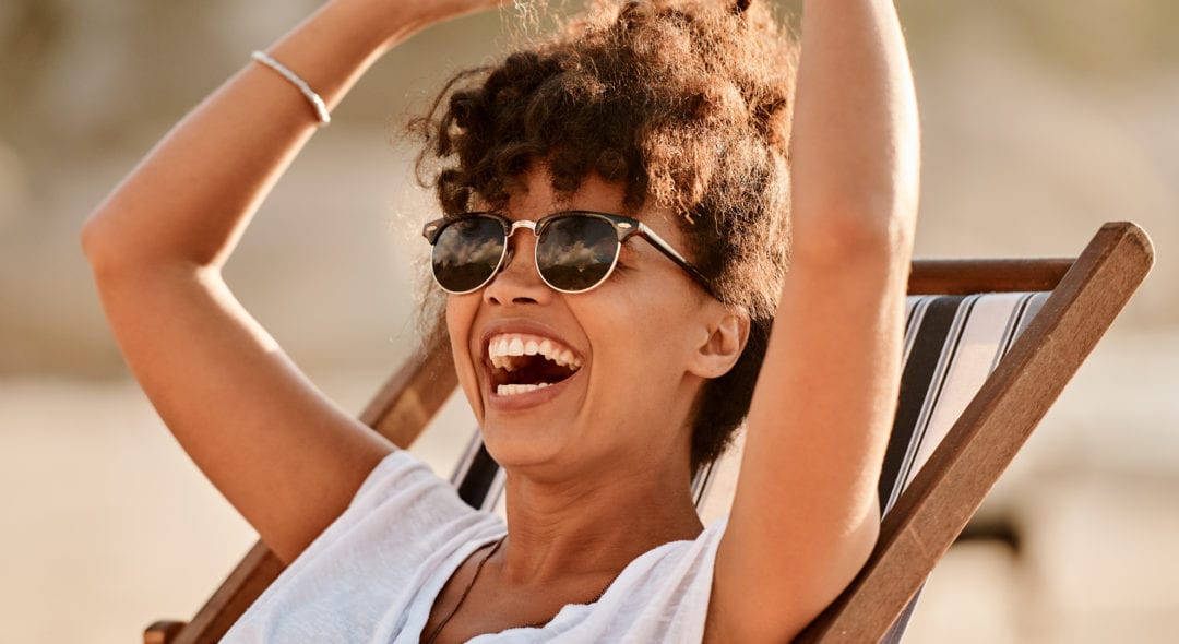 Shot of a happy young woman enjoying a summer’s day at the beach