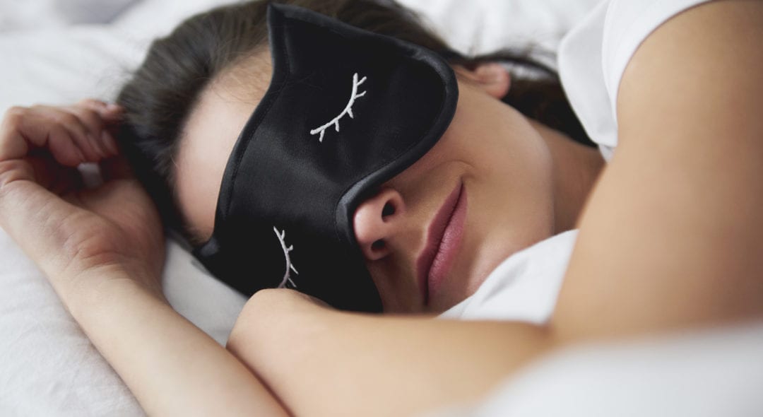 Portrait of young woman with sleep mask in bed