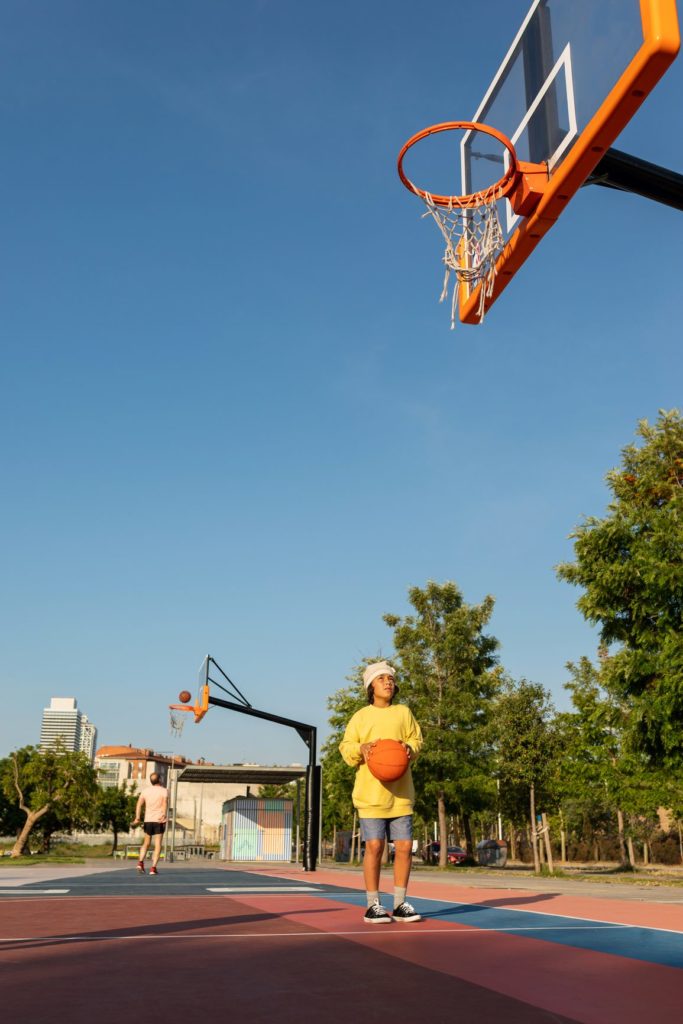 Teenage boy making a basketball shot to the basket on the basketball court