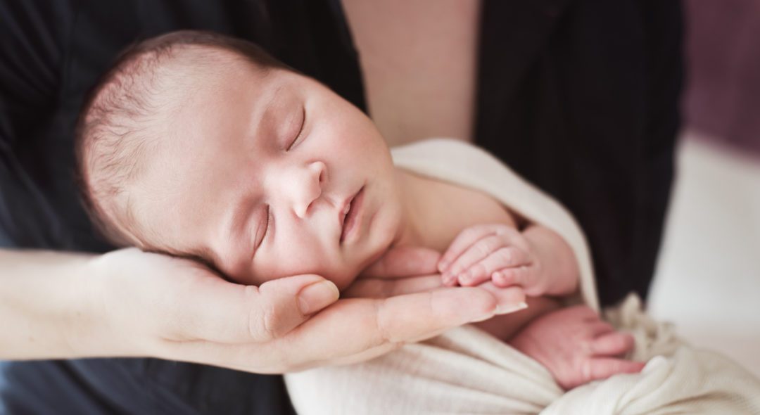 Beautiful sleeping baby resting her head on her mothers hand. She is relaxed and her hand is touching her mom's hand.