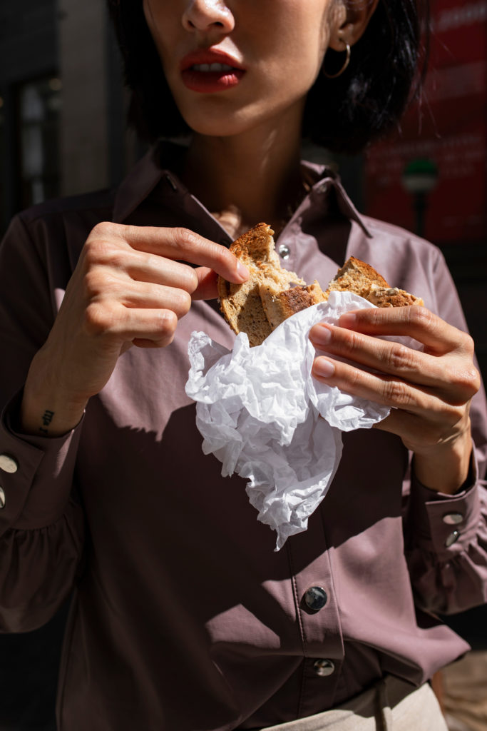 asian woman eating sandwich outside