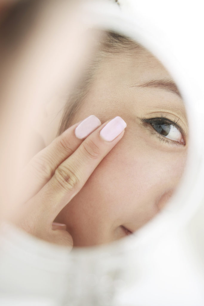 young woman looking at self in mirror,skin care