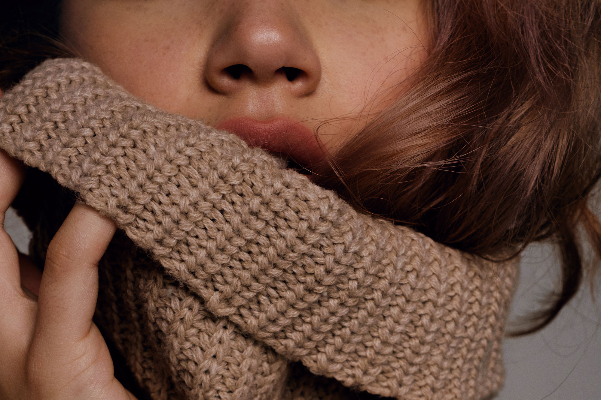 Woman pulling sweater collar up on lips