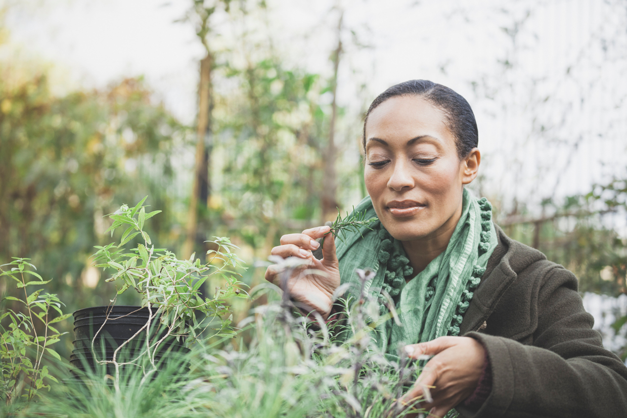 woman smelling herbs in garden