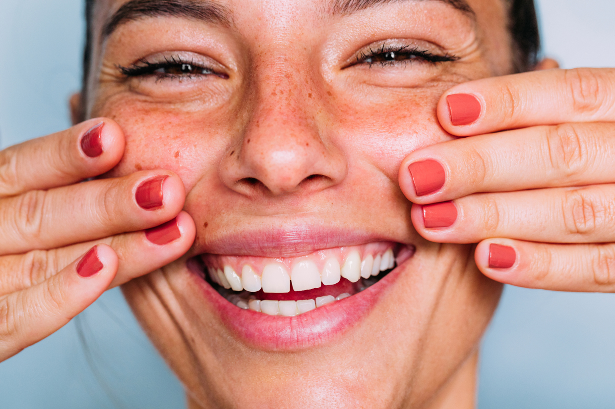 woman smiling with hands on face
