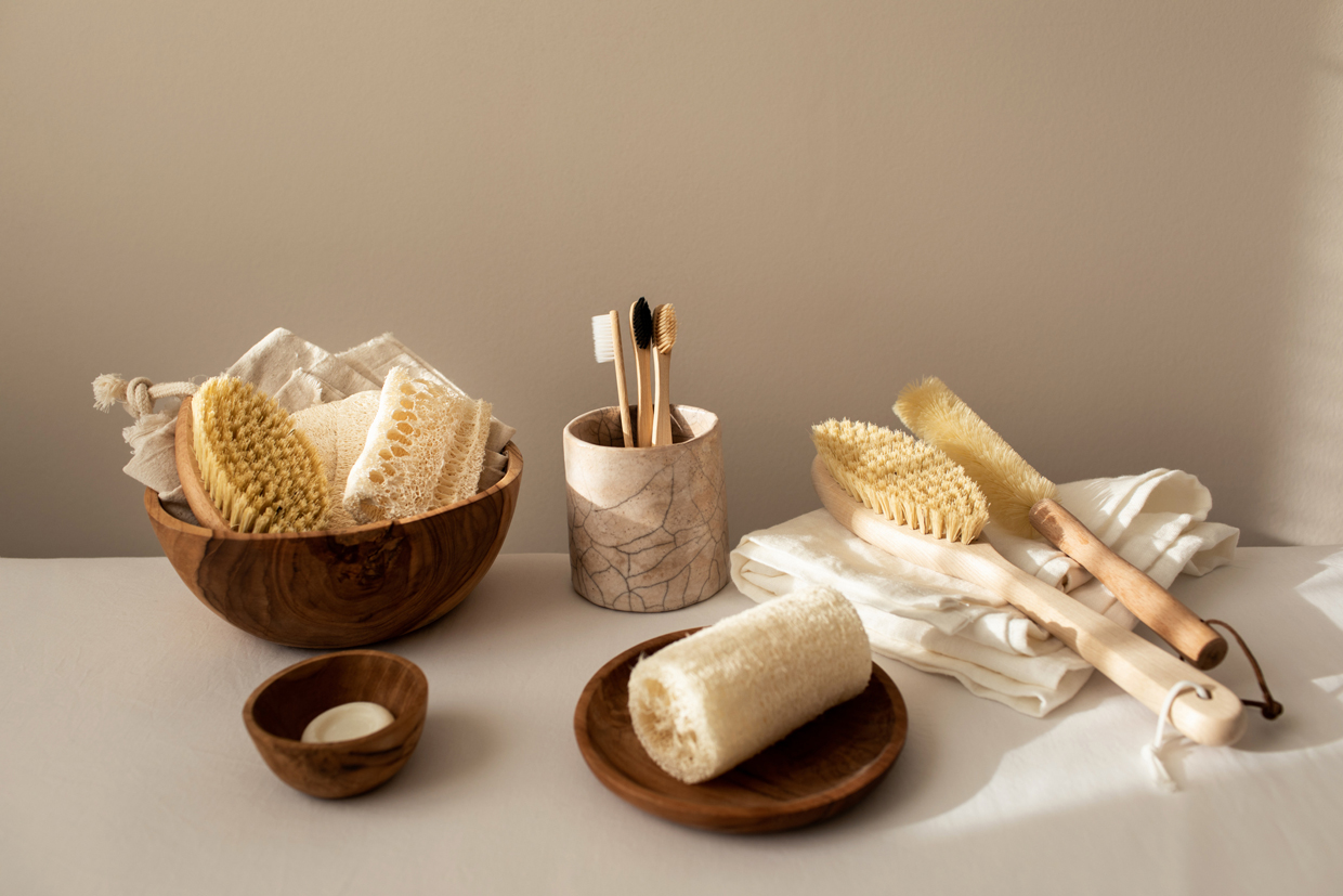 Collection of assorted kitchen and bathroom tools, organic sponges and brushes, natural soap, wood toothbrushes, linen napkin and other ecological products on beige background