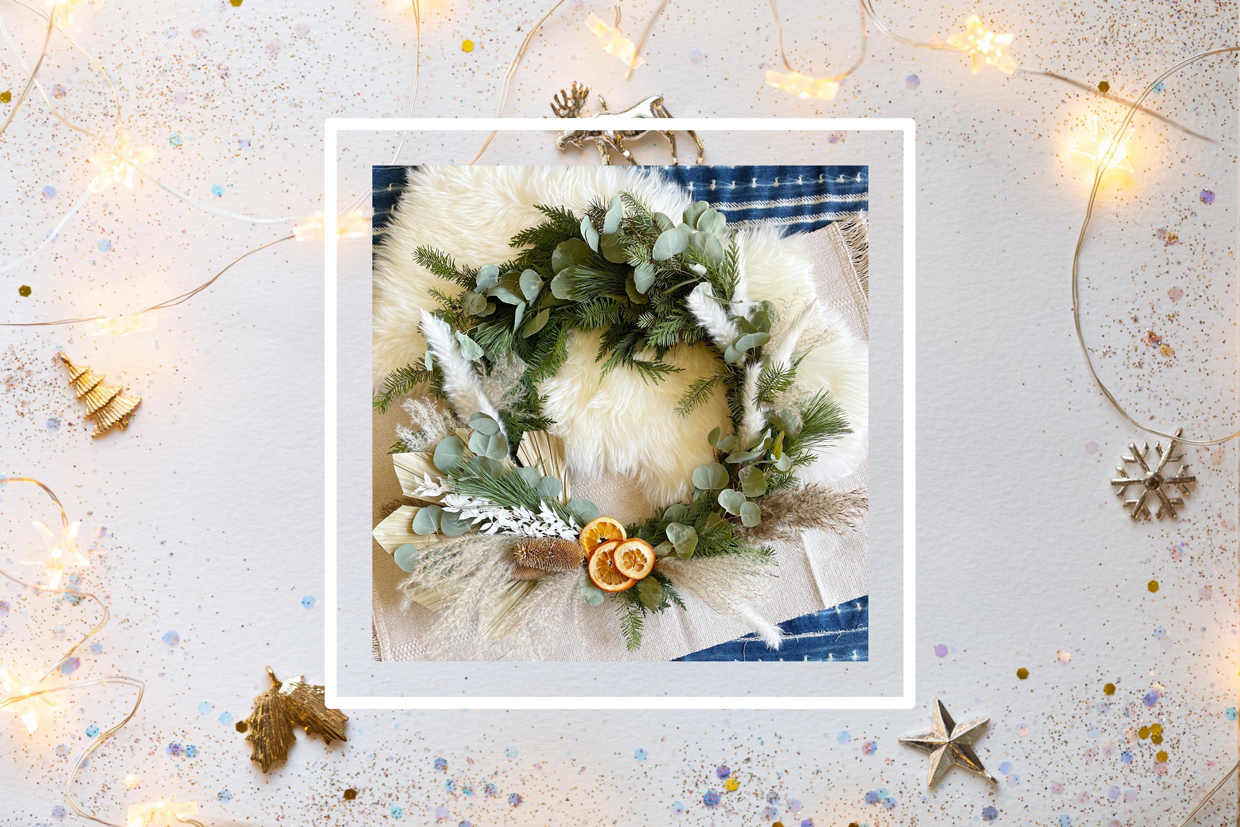 Diy wreath on paper background with holiday ornaments, sparkles and confetti.