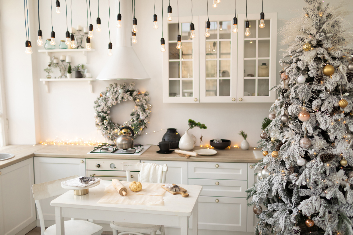 Interior white kitchen with christmas decor and decorated fir tree.