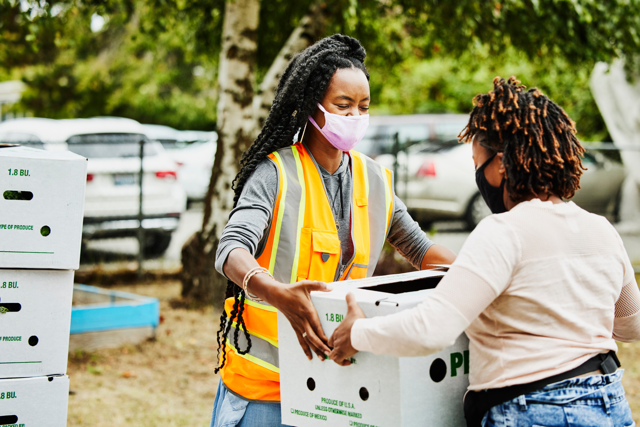 Volunteer wearing protective face mask giving away CSA box at community center