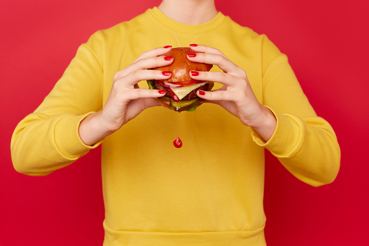 woman holding burger with ketchup dripping