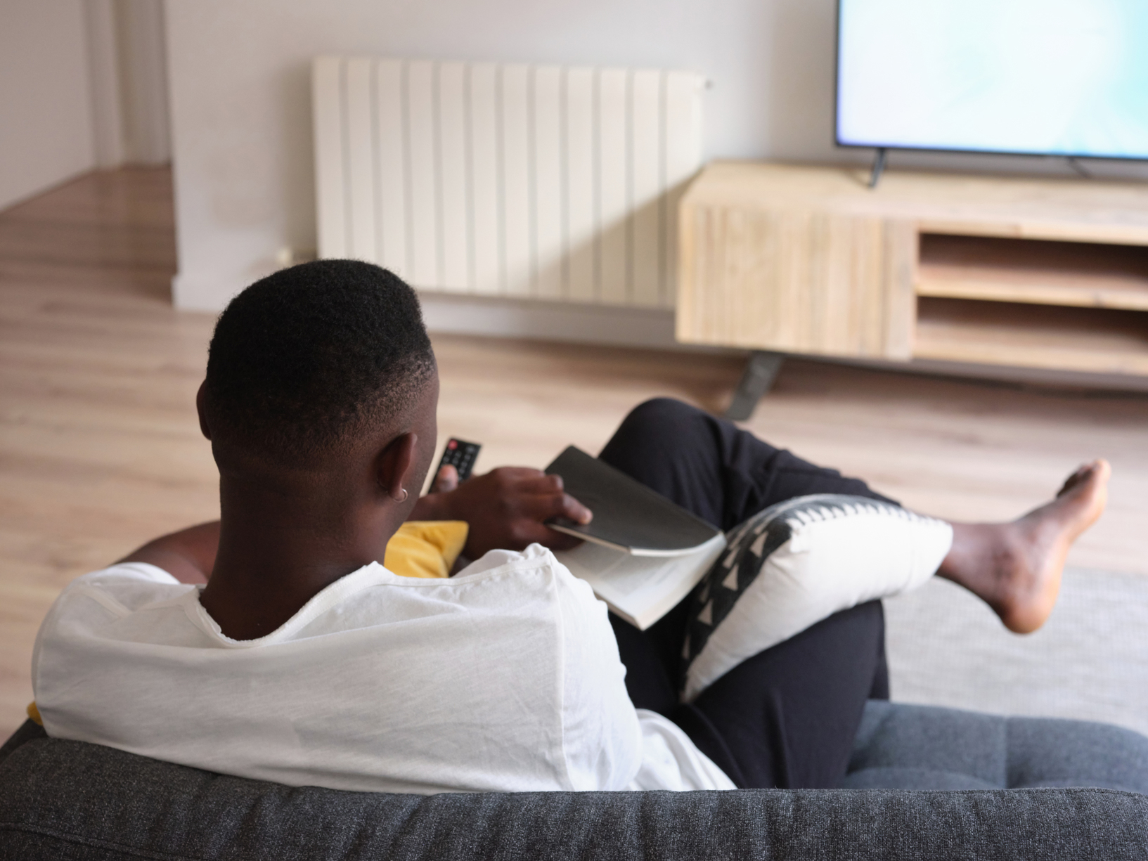 man with book and TV remote