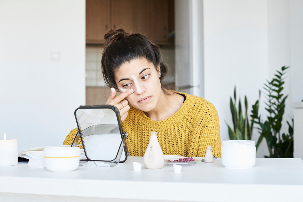 Woman applying skincare mask.