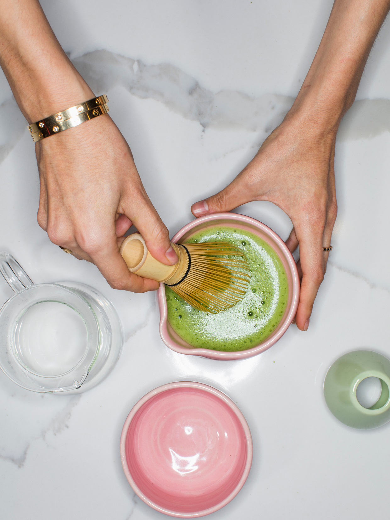 Person using whisk to prepare green tea matcha -