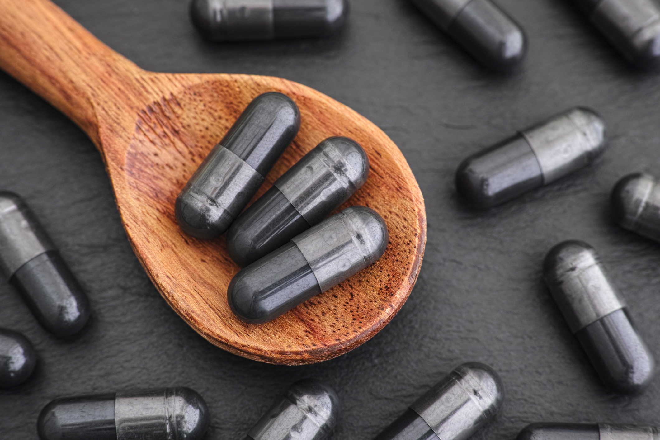 Activated charcoal capsules in a wooden spoon 