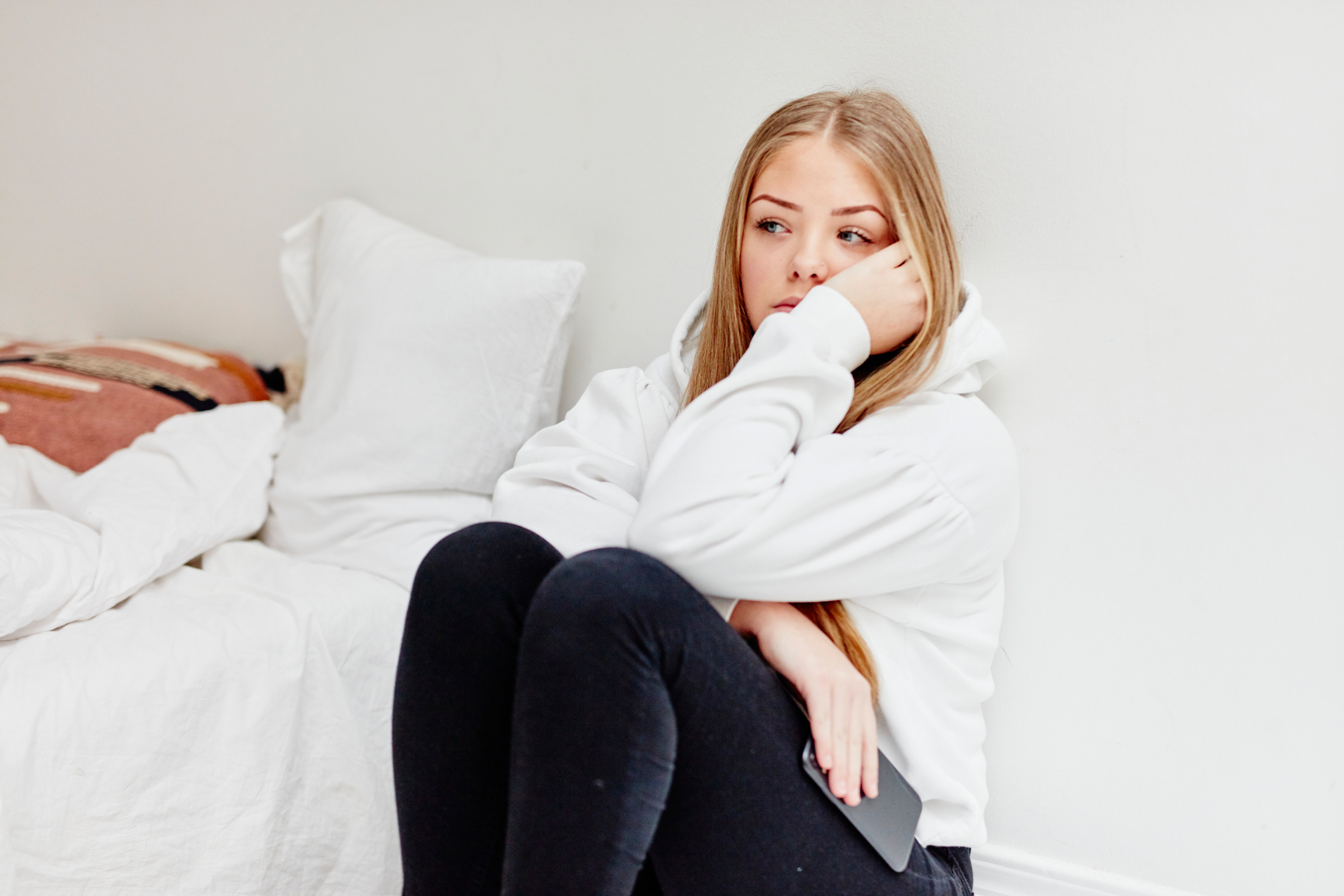 worried teen girl sitting in bedroom