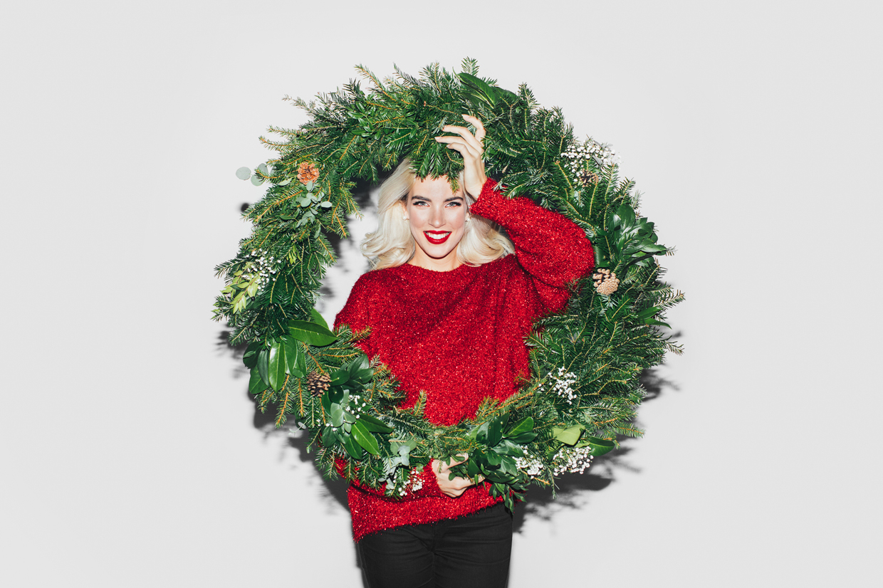 woman with red sweater holding holiday wreath