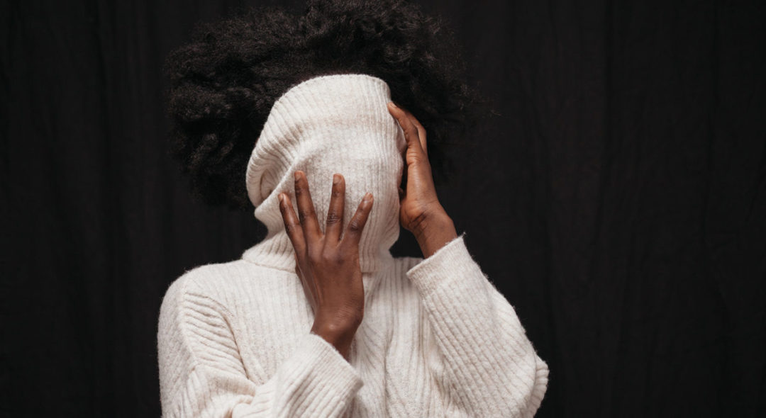 woman covering face with sweater