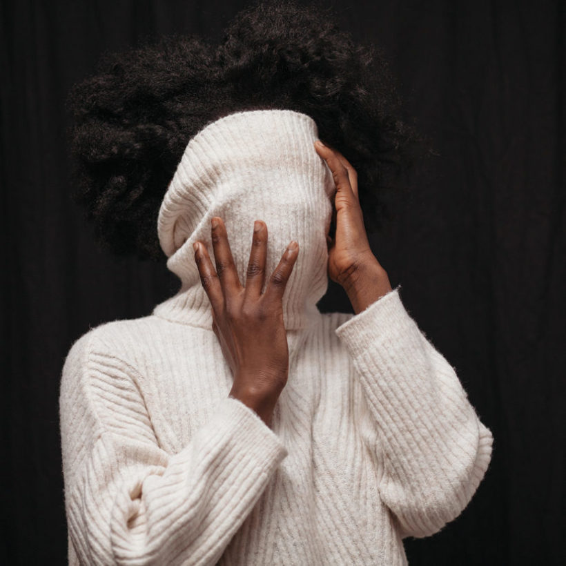 woman covering face with sweater