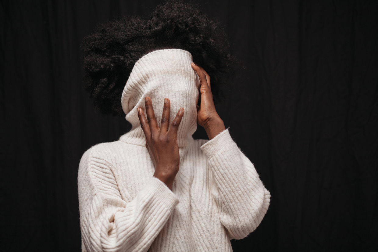 woman covering face with sweater