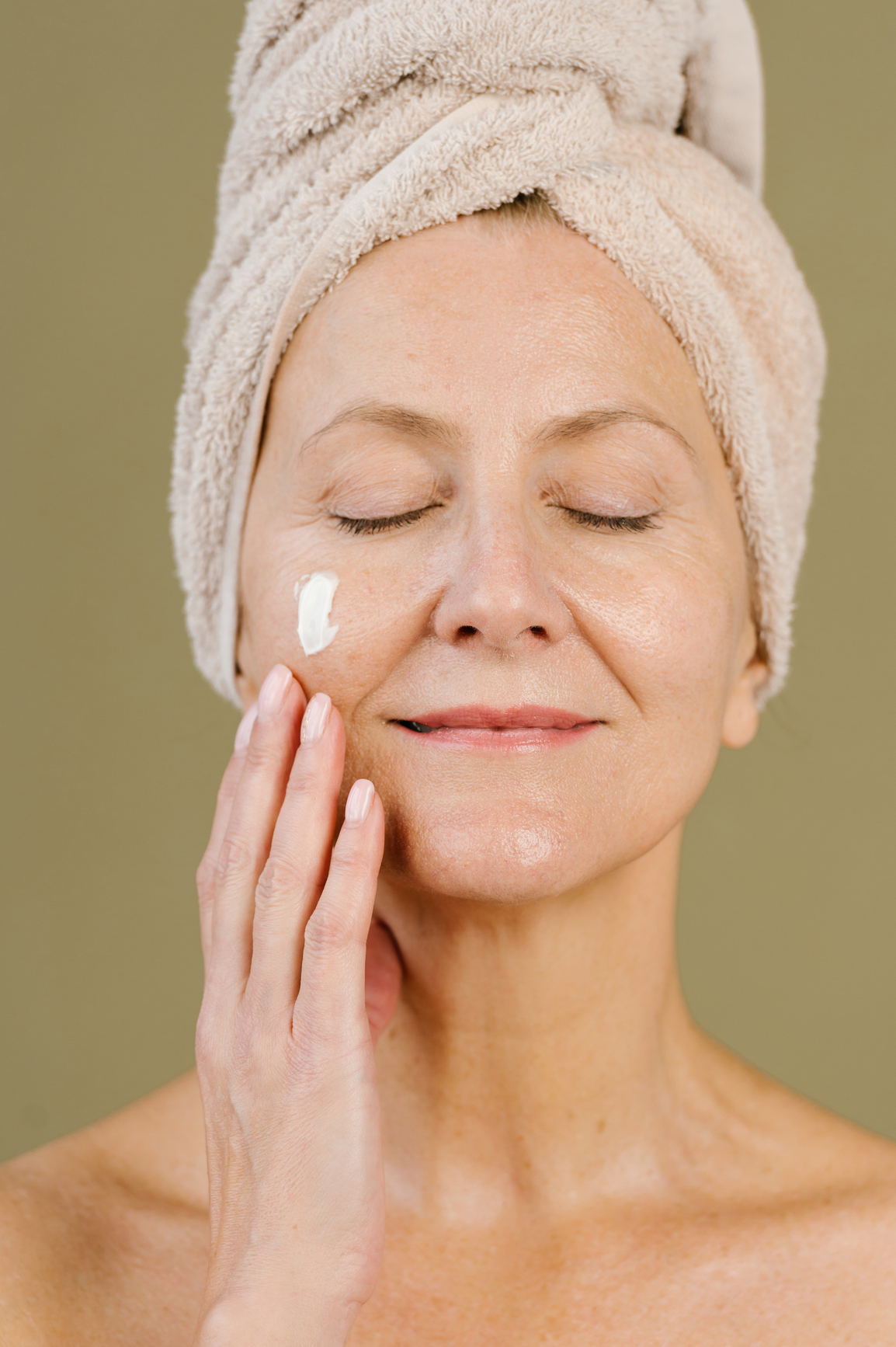 woman applying facial cream in studio
