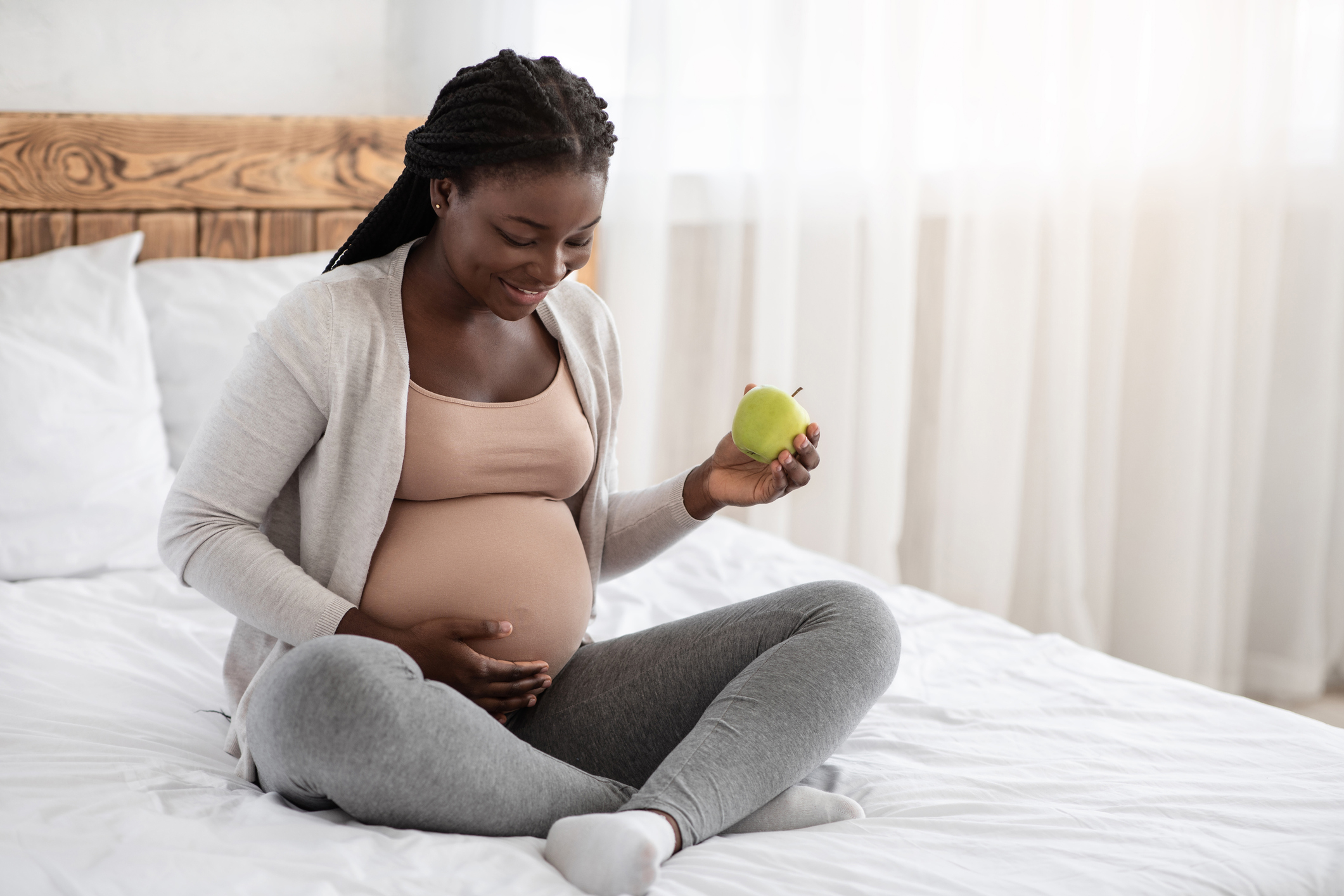 pregnant woman eating an apple in bed