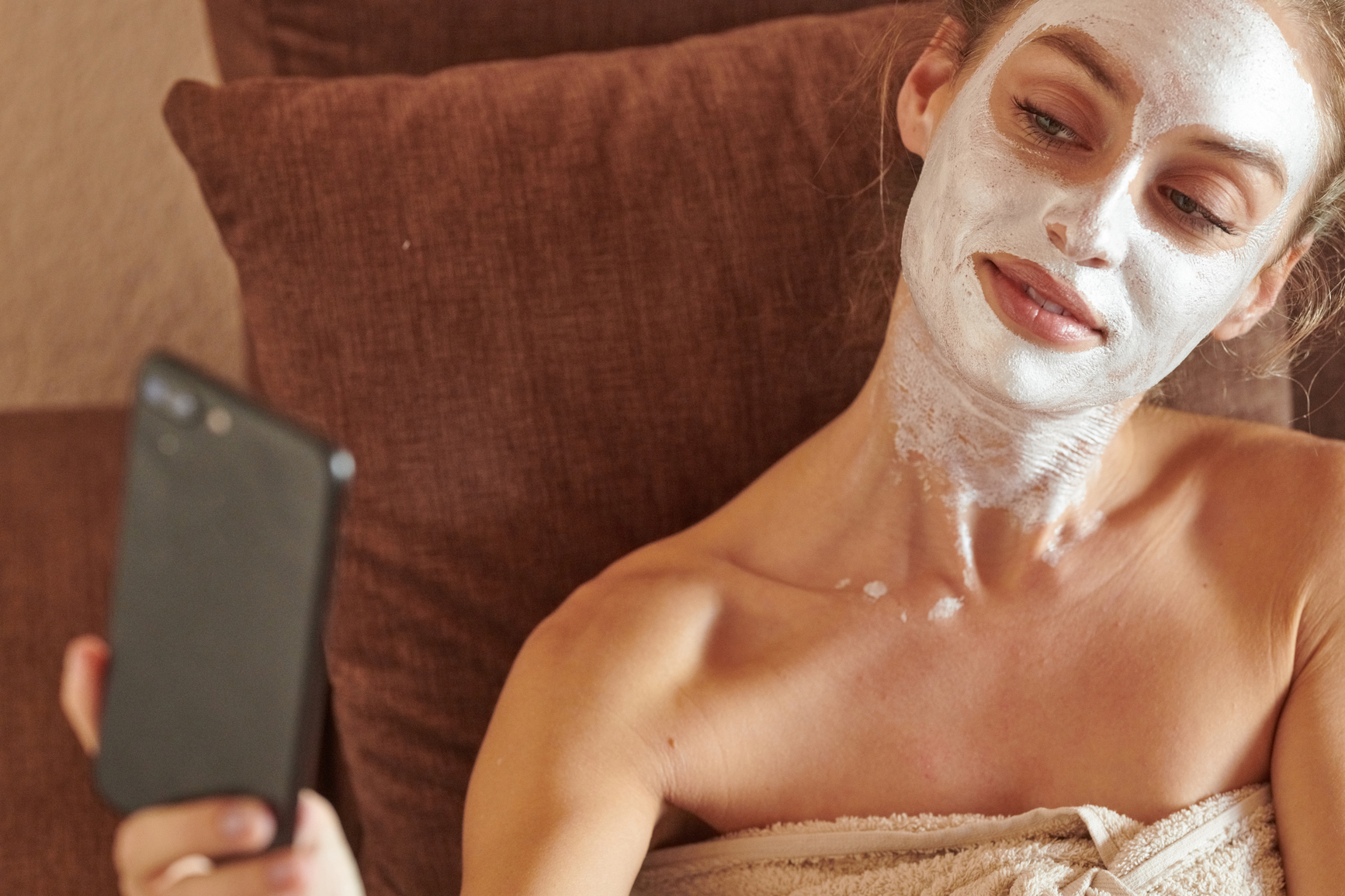 woman with face mask taking selfie at home