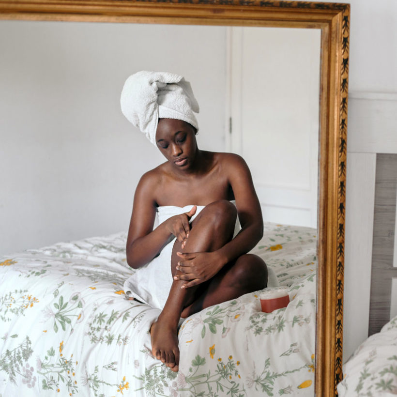woman applying lotion in bedroom