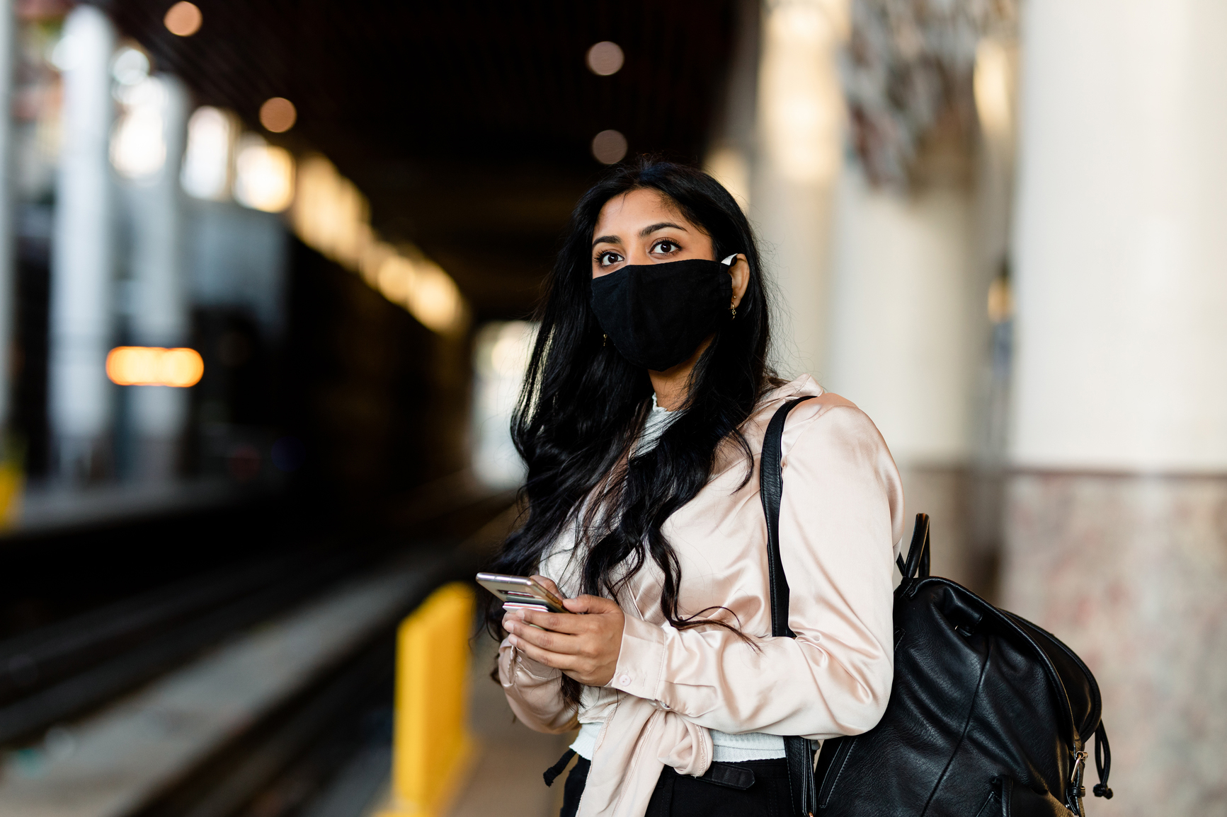 woman with a mask waiting in train station