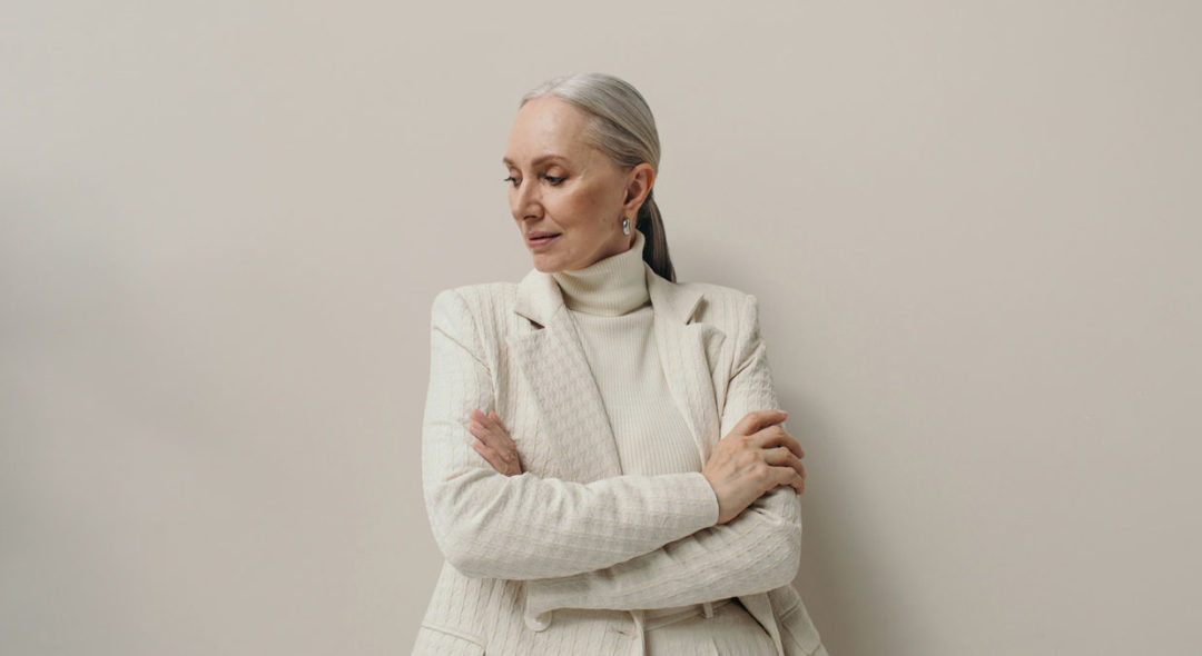 in studio shot of woman with gray hair wearing all white