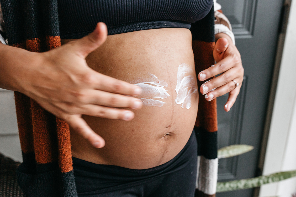 pregnant woman applying lotion on stomach
