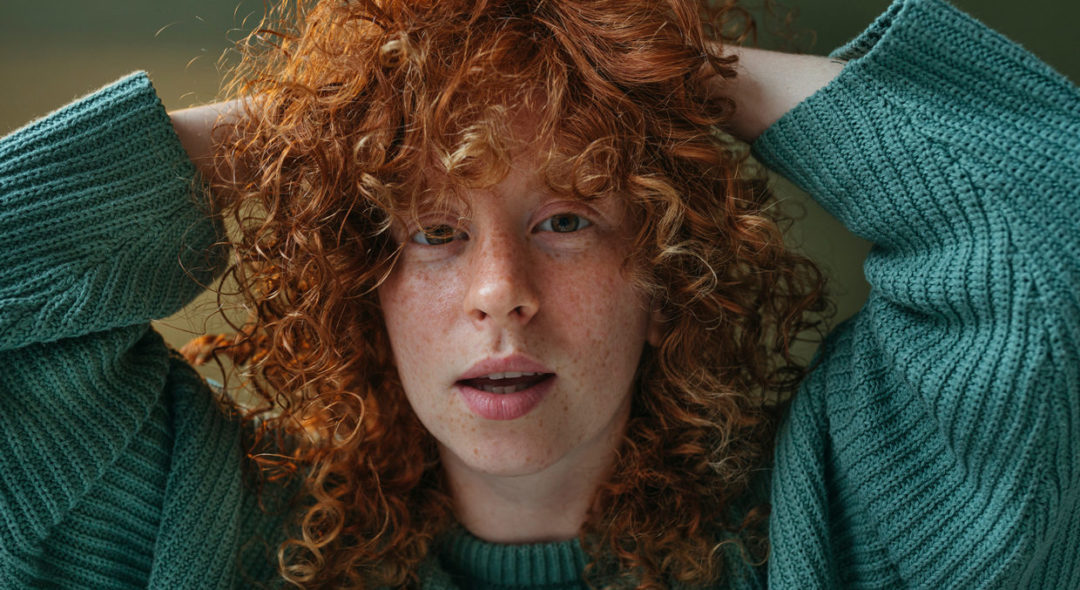 portrait of red haired woman grabbing hair