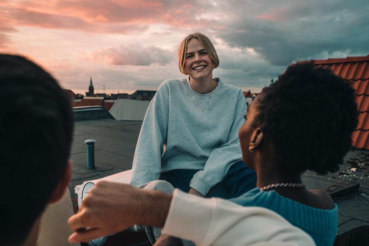woman sitting with friends on building terrace during sunset
