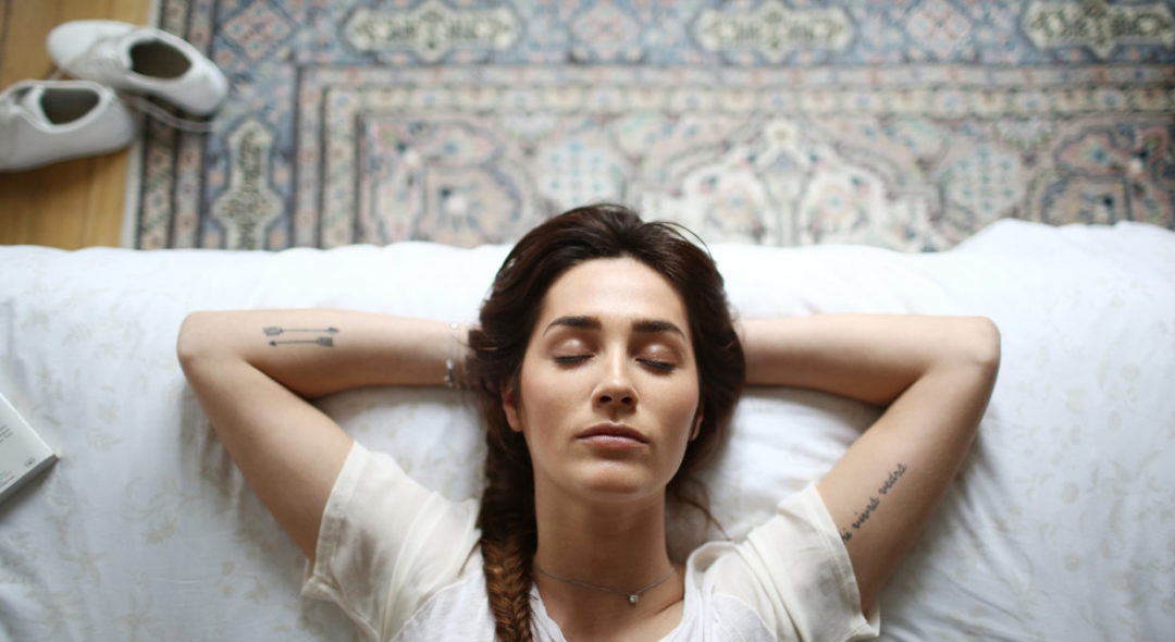 woman with closed eyes laying in bed