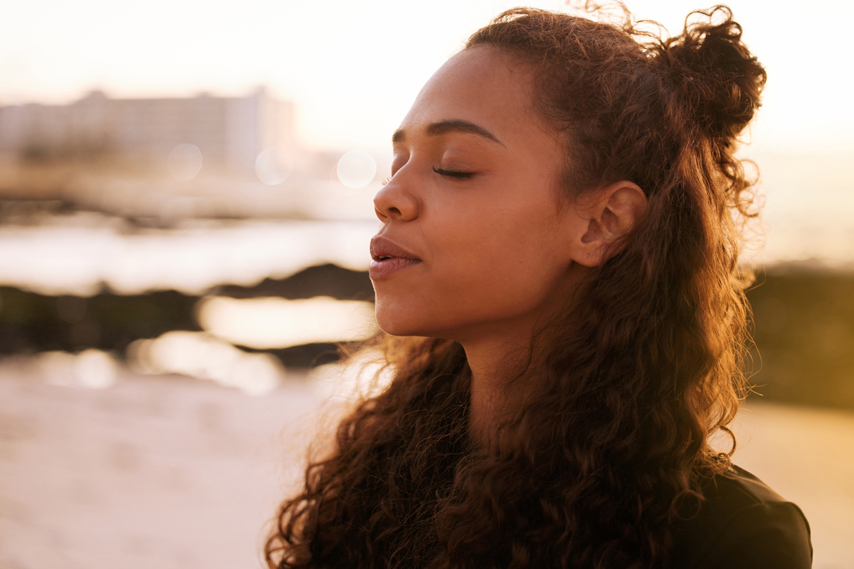 woman closing eyes meditating in beach