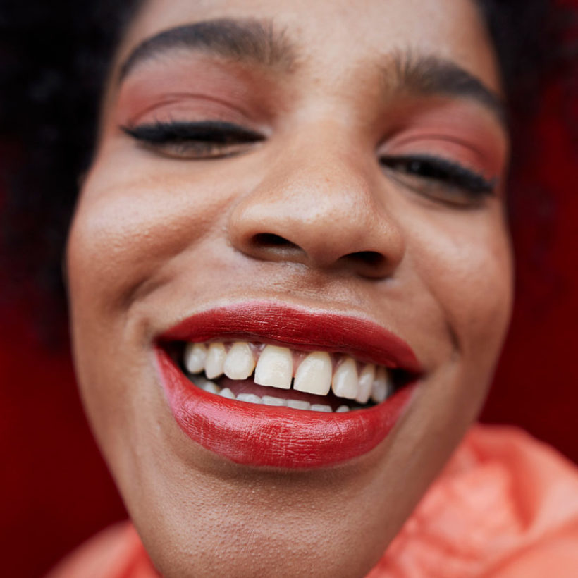 Close-up of smiling woman against red wall