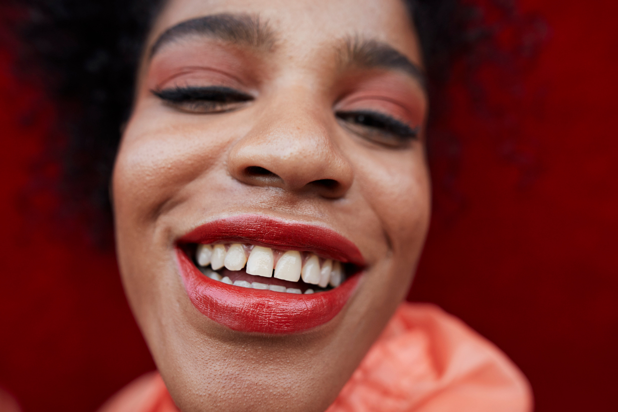 Close-up of smiling woman against red wall