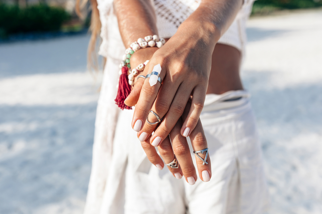 closeup of woman's hands with rings on beach