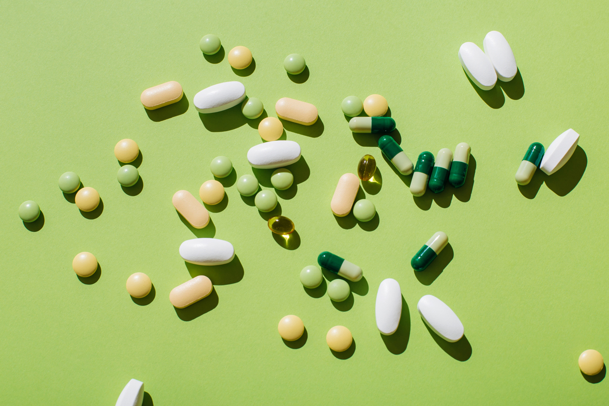 Colorful pills and capsules on green background