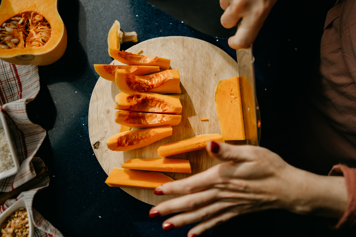 woman slicing a Butternut Squash on a wooden cutting board