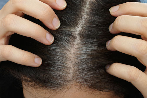woman shows her gray hair roots