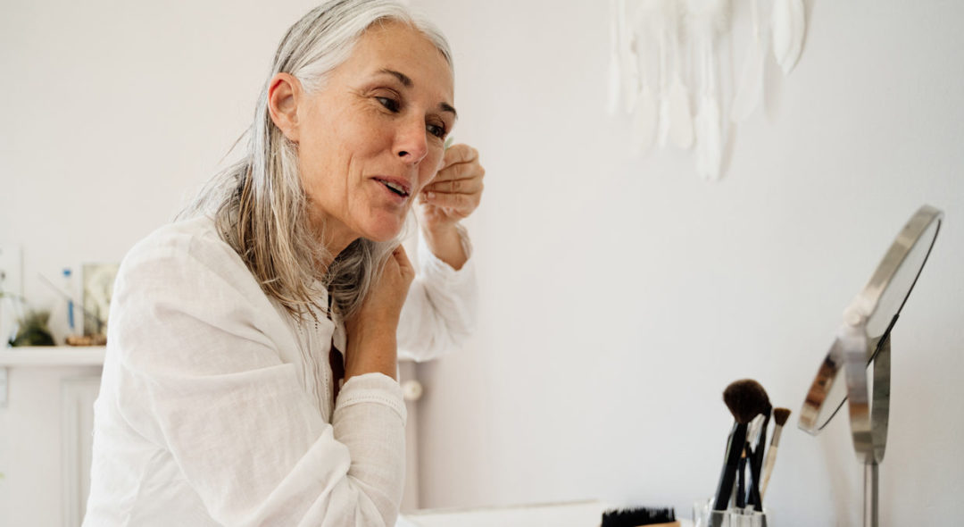 woman doing skin care in mirror at home