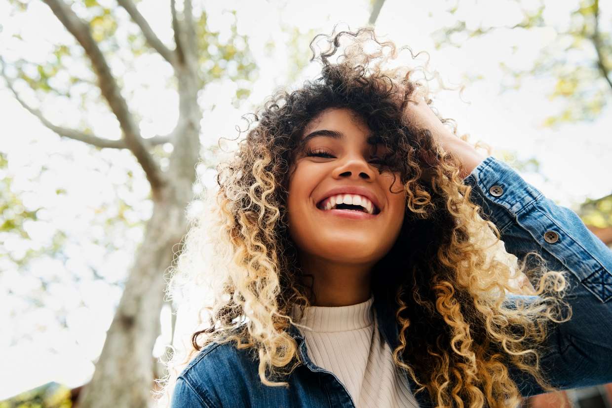 curly haired woman smiling outside