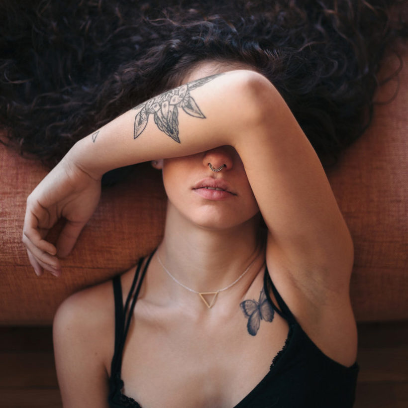 Young tattooed woman covering her face