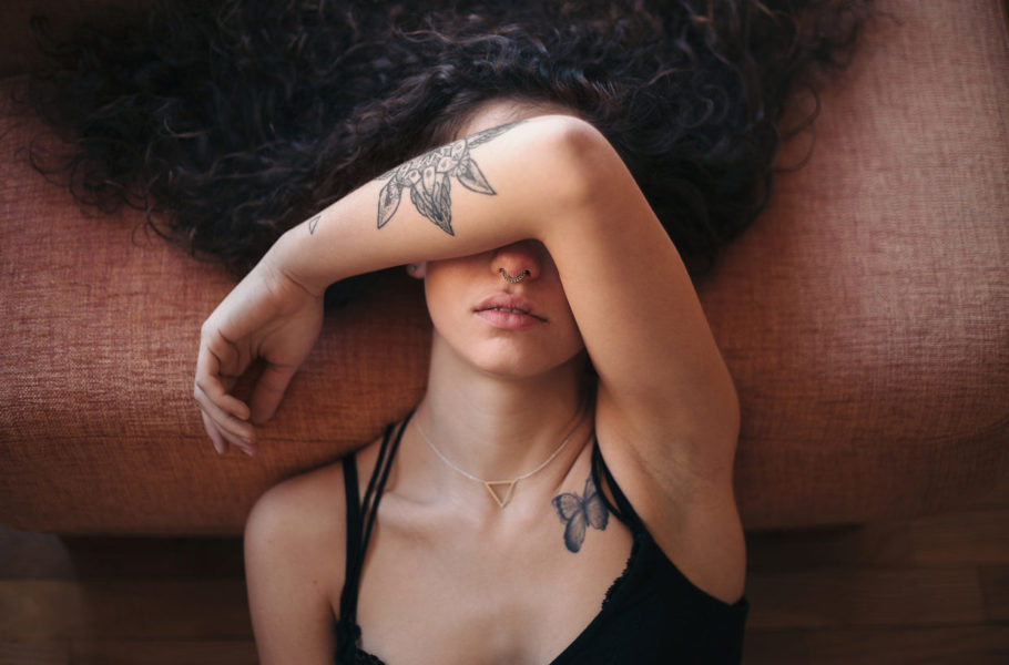 Young tattooed woman covering her face