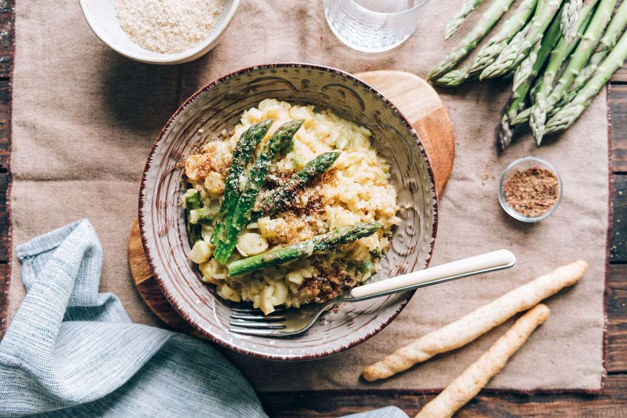 Overhead shot of Italian risotto with asparagus topped with ground flaxseed, almonds and walnuts.