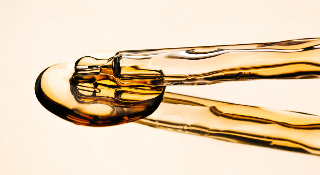 oil in glass pipette on luxury gold reflective surface