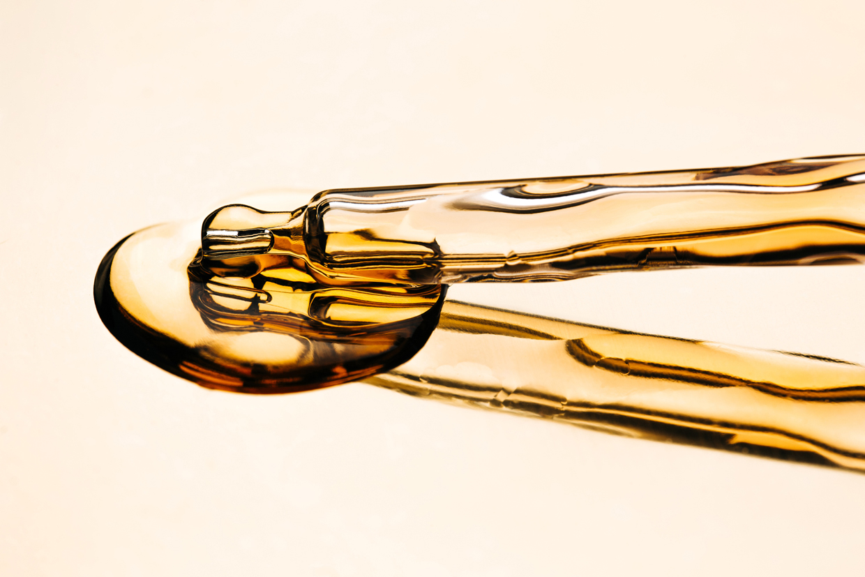 oil in glass pipette on luxury gold reflective surface