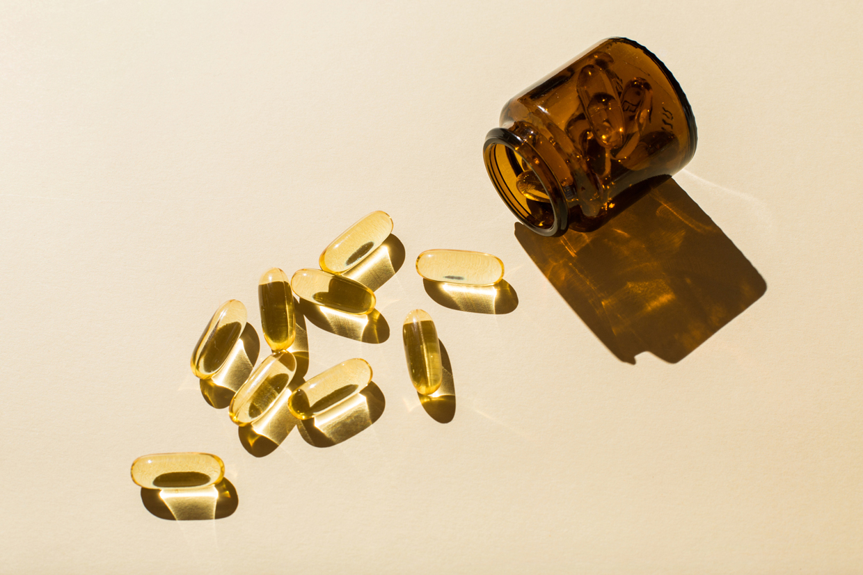 Omega 3 fish oil capsules and a glass bottle on a beige background